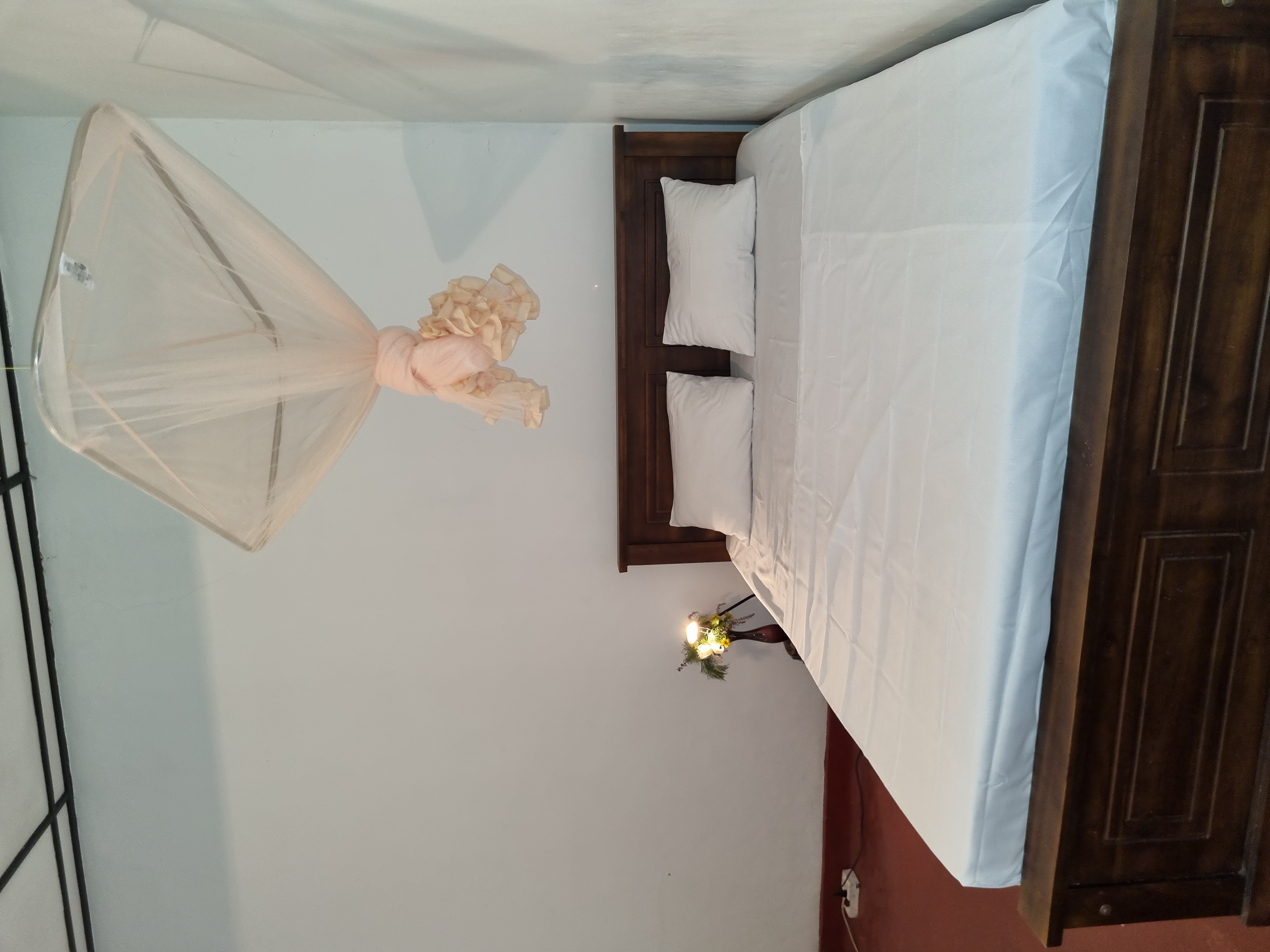 Bedroom with mosquito net and ceiling fan at Lion Shade Bungalow